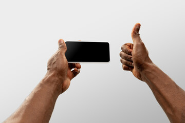 Thumb up, like. Close up male hands holding smartphone with blank screen during online watching of popular sport matches, championships. Copyspace for ad. Devices, gadgets, technologies concept.