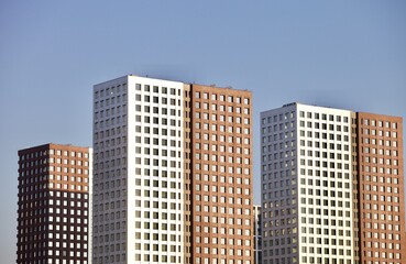 Obraz premium Residential skyscrapers on clear blue sky background. Commercial real estate. Modern residential city district. Apartment buildings architecture. New Property For Sale. New buildings exterior design.