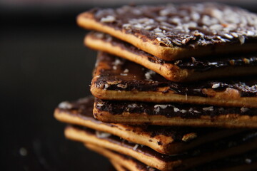dry bread with the basis of wheat with a mixture of chocolate, sugar and grated coconut. snacks with sweet and salty taste. wafer with a dark background