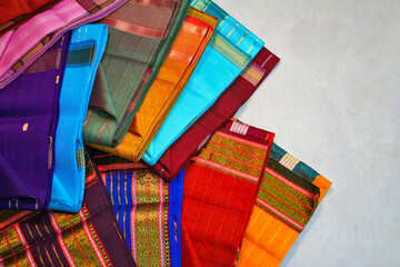 Maheshwari saris in a textile shop, displayed in front of customers. Maheshwar, Madhya Pradesh, India.