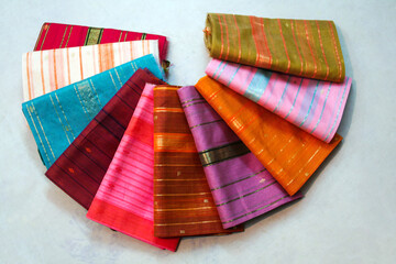 Maheshwari saris in a textile shop, displayed in front of customers. Maheshwar, Madhya Pradesh, India.