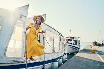 Travel by greece. Pretty young traveling woman in ellow dress boarding on ferry boat taxi, Poros...