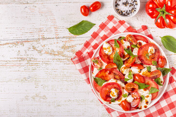 Italian caprese salad with sliced tomatoes, mozzarella cheese, basil, olive oil, balsamic vinegar.