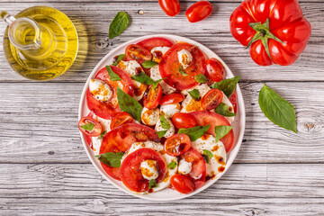 Italian caprese salad with sliced tomatoes, mozzarella cheese, basil, olive oil, balsamic vinegar.