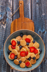 Trendy breakfast with mini pancakes, blueberries and strawberries