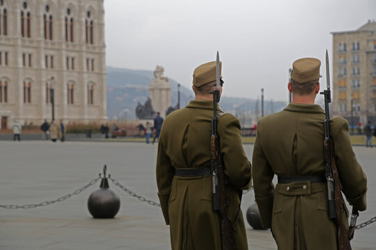 Pair of Hungarian military soldiers are patrolling and scanning the Kossuth Lajos square in Budapest,for threats and to intimidate possible criminals.Their khaki uniform and bayonet rifle are visible.