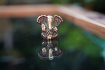 Ganesha deity in bronze on glas reflecting