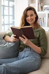 Fototapeta premium Woman reading book while sitting on the couch