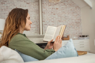 Woman reading book while sitting on the couch