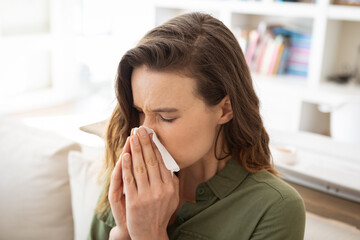 Woman blowing her nose at home