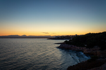 A beautiful sunset in a coast of Salou (Spain) with a blue sky and rocks