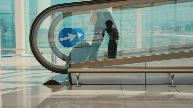Urban modern times traveler stand on moving walkway in airport terminal. Man walk onto walkway with suitcase, rush to gate or delayed flight. New normal concept, social distancing and empty airport 