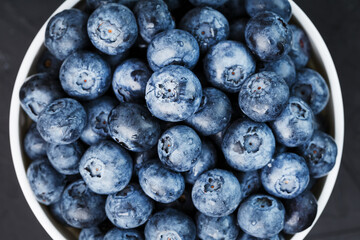 Organic blueberries in a white Cup on a black Board.