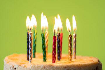 Burning candles in birthday cake. Close up of colorful candles flame in homemade cake. Sweet dessert for birthday party. 