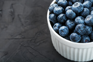 Organic blueberries in a white Cup on a black Board.
