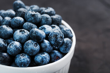 Organic blueberries in a white Cup on a black Board.