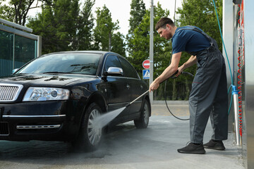 A man washes a car in a manual car wash. Clear car