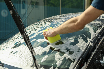 Man wipes the car with a sponge. Car wash. Clear car concept