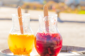 Yellow red big bowls of punch at vacation holiday bar. Fresh cool juicy orange pineapple juice and wine sangria in sunny summer. Tropical refreshment cocktail drink at holiday beach party