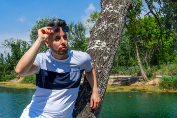 Young man in white pants and modern styling posing in the freshwater pond of Clot De La Mare De Deu in Burriana