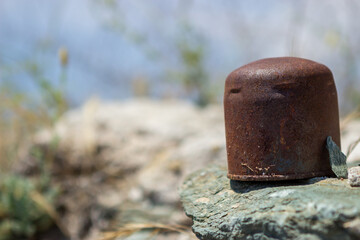 Selective focus on old rusty oil filter. The filter is on the beach and pollutes the beautiful nature.
