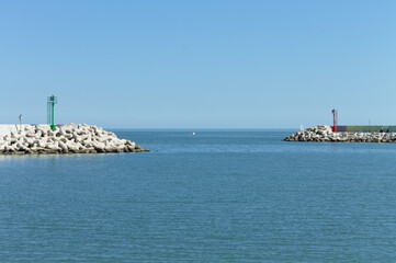 The entrance of Pesaro harbour with tetrapod breakwaters, and a green and a red lighthouse on the piers (Marche, Italy, Europe)