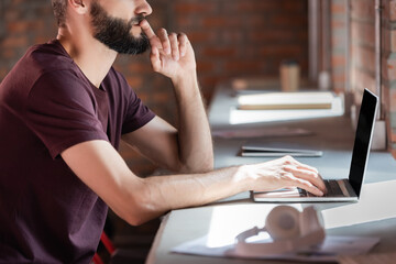 selective focus of bearded businessman using laptop near wireless headphones