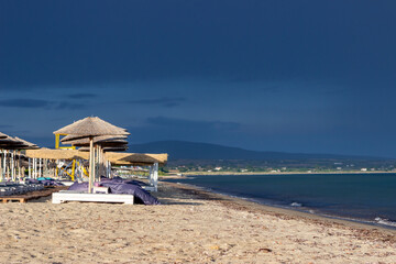 The dark blue sky is above the beach by the sea. It's like a storm. The beach is empty and there are no people.