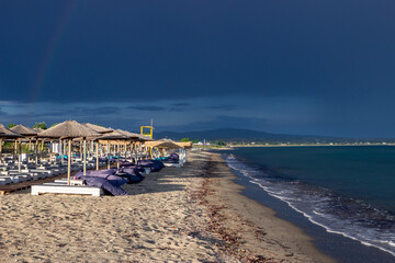 The dark blue sky is above the beach by the sea. It's like a storm. The beach is empty and there are no people.