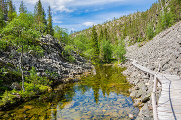 View of The Pyha-Luosto National Park in summer, rocks, stones, trees, wooden walkway and natural pond, Lapland, Finland