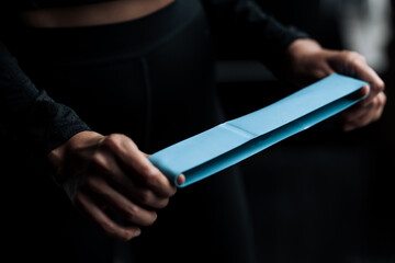 Close-up shot of female hands pulling a blue sports rubber band for training to strengthen body...