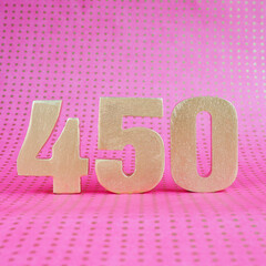 450 golden volumetric digit on a bright pink polka dot background. copy space..