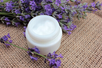 Obraz na płótnie Canvas DIY face or eye cream with fresh lavender flowers on burlap fabric texture. Organic herbal cosmetic concept. Selective focus 