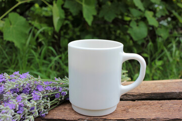 Cup of coffee with milk or cappuccino and lavender flowers on wooden board in summer garden. Enjoying morning coffee. Top view, copy space. Selective focus