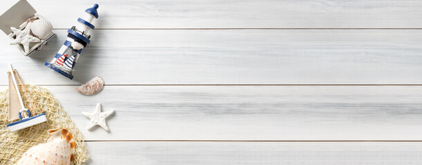 Top view summer rustic blue lighthouse and seashell decorate on white wooden table with sunlight...