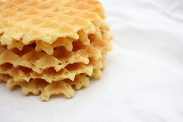Stack of waffles on a white fabric texture background. Top view, copy space