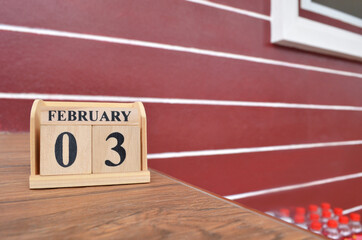 February 3, Number cube with wooden table beside the wall.