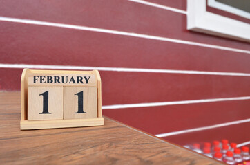 February 11, Number cube with wooden table beside the wall.