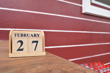 February 27, Number cube with wooden table beside the wall.