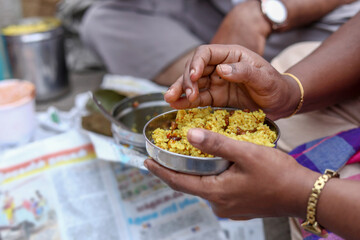 view of Indian man hand eating Tamarind Rice on ground from Tamil Nadu, India