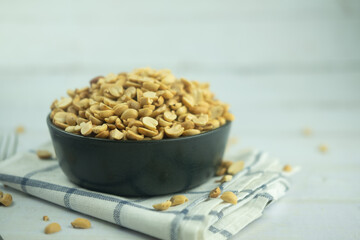 Many roasted peanuts in black bowl