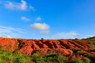 Naklejka premium The red land is under the blue sky and white clouds.