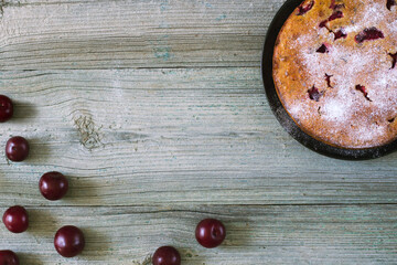 Beautiful delicious plum cake and scattered juicy plums on a wooden background, top view, place for text