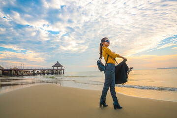 A woman walks along the beach taking photos at sunrise and sunset.