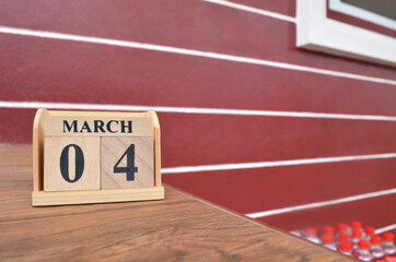 March 4, Number cube with wooden table beside the wall.