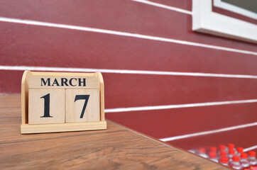 March 17, Number cube with wooden table beside the wall.