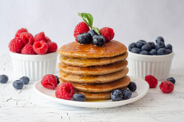 Pancakes with forest fruits berries on white table. Healthy breakfast. Blueberries, raspberries on pancakes.