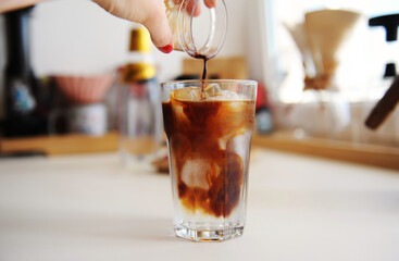 Making espresso tonic. Pouring espresso into glass with tonic and ice