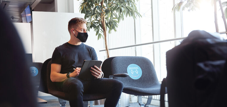 Male waiting in airport wearing protective face mask
