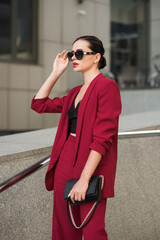 Bussines lady in red suit stands near office. Soft selective focus.